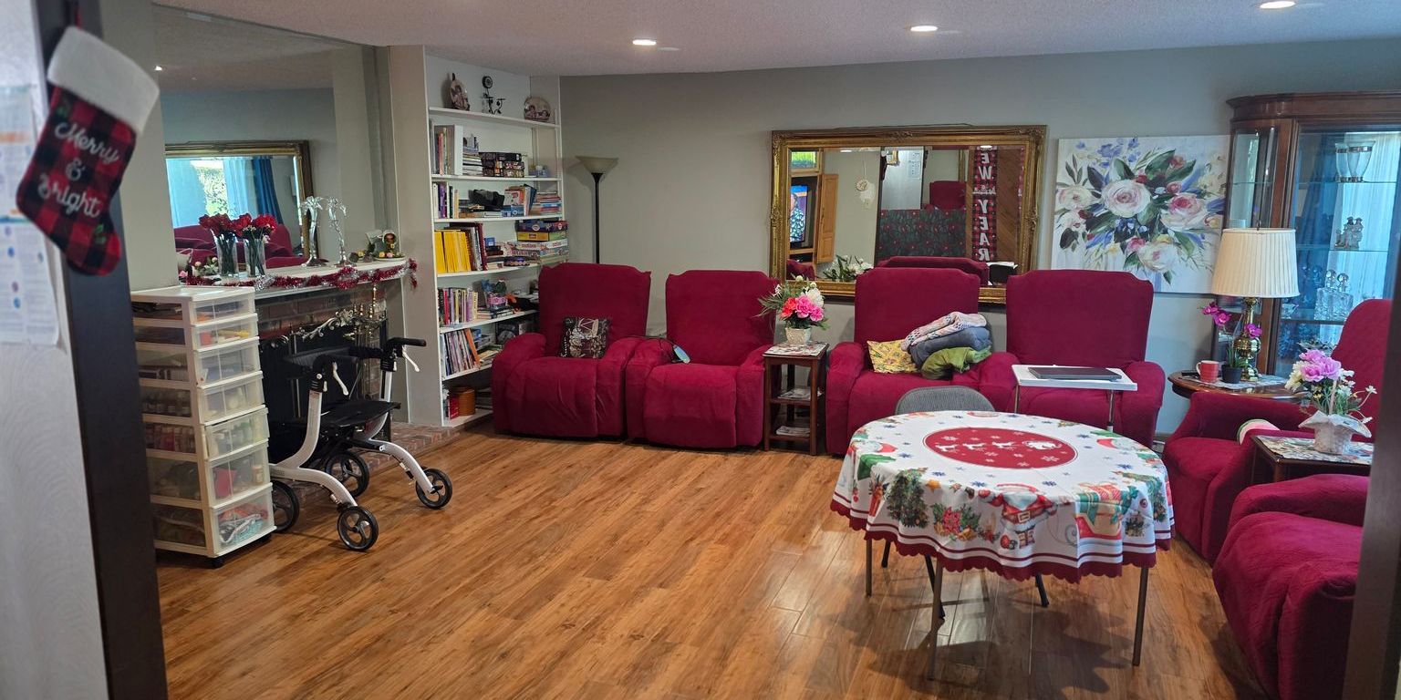 A house with navy blue siding and white doors is partially shaded by a tree with bright red and orange autumn leaves, similar to the warm, welcoming appearance of Auburn adult family homes.